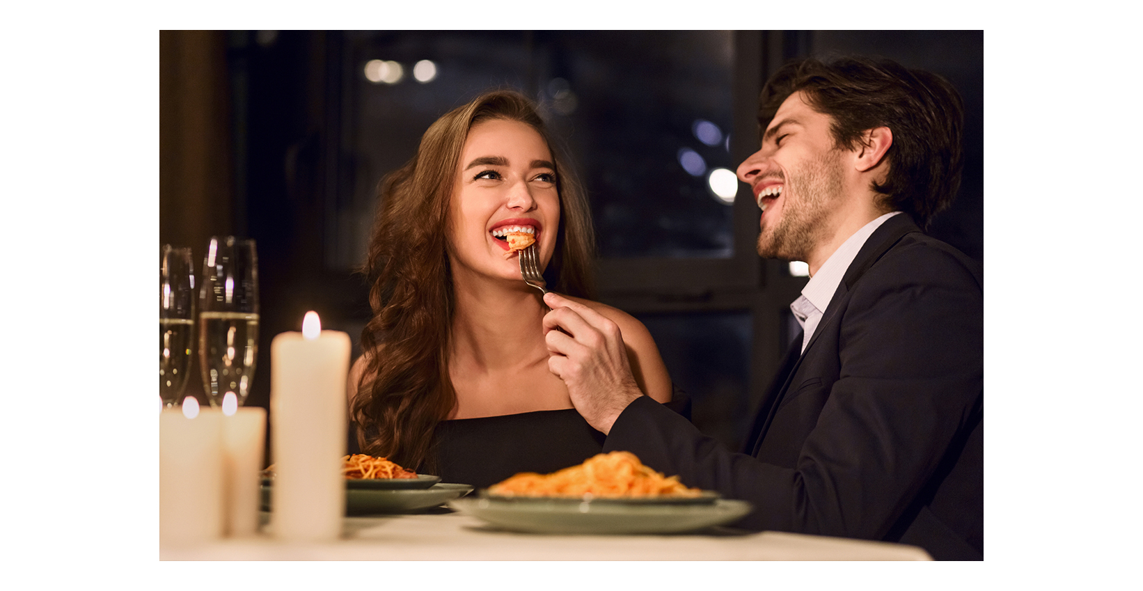 A couple eating food at a restaurant and laughing