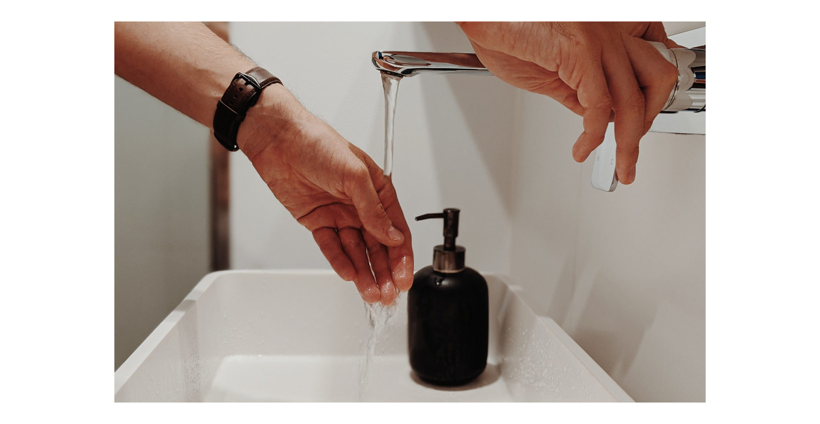 A man washing his hands in a bathroom sink